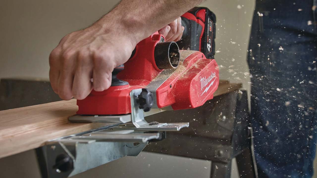 Milwaukee elhøvl med spåner på vej ud af støvsugerudtaget